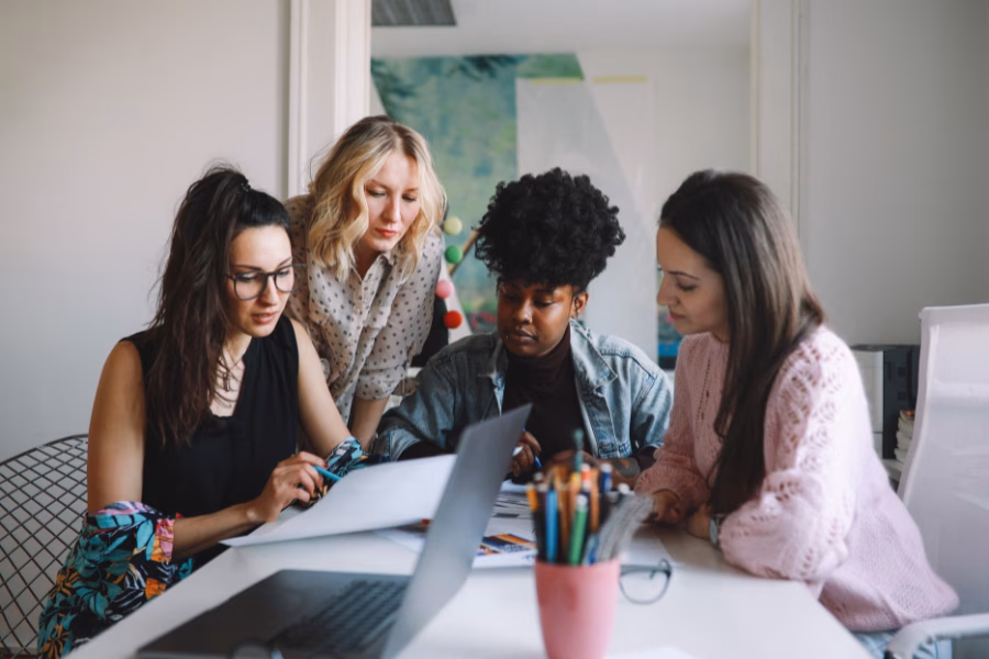 A group of young women at work - they are looking at a piece of paper