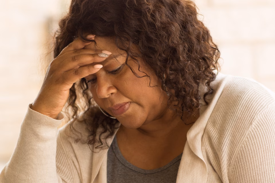 A black woman with curly shoulder length looking sad