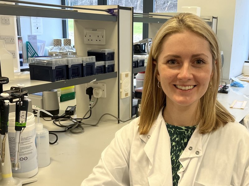 Dr Marianne Watters, Wellbeing of Women researcher, standing in a laboratory smiling to the camera