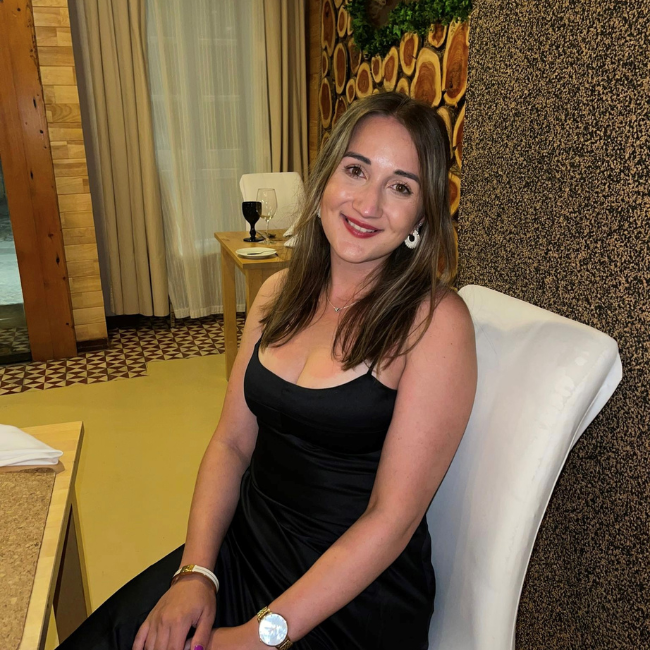 A young white women sitting down in a black dress