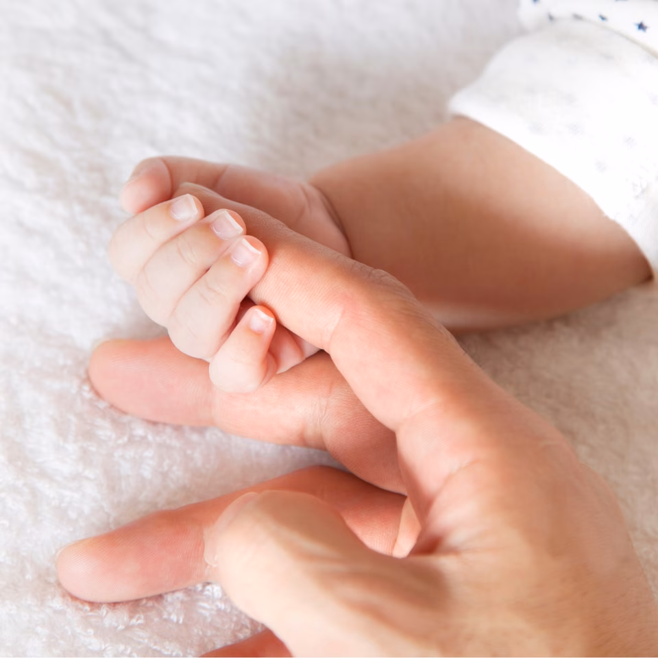 A mother holds the hand of her baby