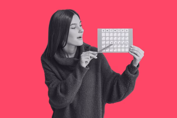 A teenager holding a pen and pointing at a menstrual calendar.