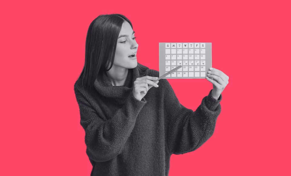 A teenager holding a pen and pointing at a menstrual calendar.