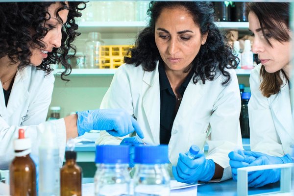 Three women researchers working together and talking in a laboratory setting